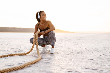 Image of african american sportswoman working out with battle ropes