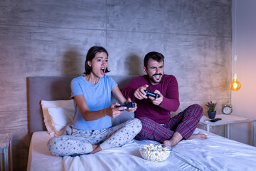 Couple having fun playing video games in bed