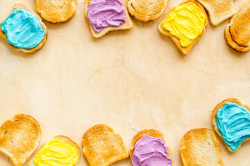 Funny toasted bread with colored cheese spread. Overhead view