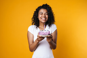 Image of happy african american woman holding birthday cake with candle
