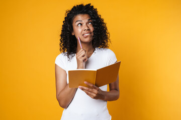 Image of thinking african american girl posing with exercise book