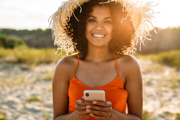 Smiling young african woman using mobile phone
