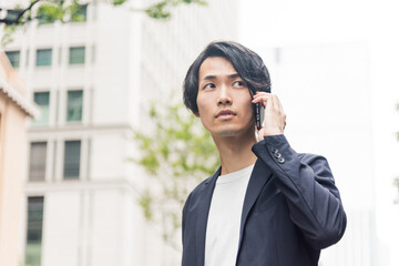 オフィス街で電話をする若い男性