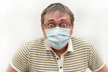Portrait of a man in medical mask with glasses and bulging eyes. Humor, emotion