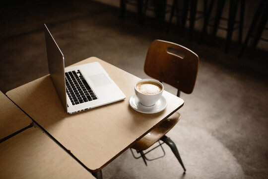 laptop at angle on desk with latte on corner