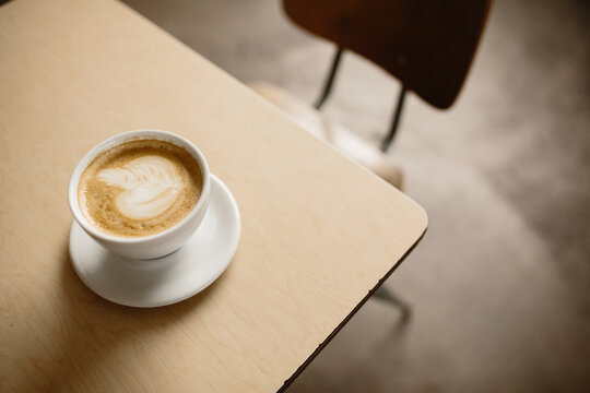 latte in white cup and saucer on table corner