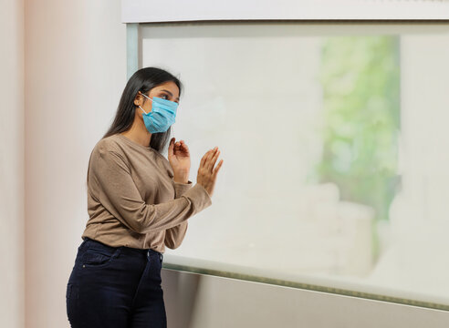 Woman looking out of the window during lockdown hoping for situation to get better	