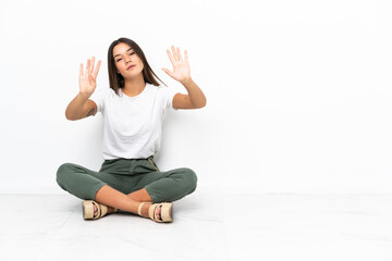 Teenager girl sitting on the floor counting nine with fingers