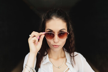 Woman in sunglasses in a dark hallway.