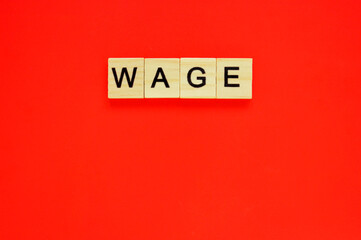 Word wage. Wooden blocks with lettering on top of red background. Top view of wooden blocks with letters on red surface