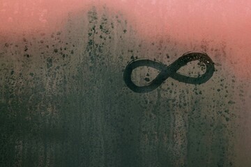 condense on a window glass and an infinity sign drawn by finger
