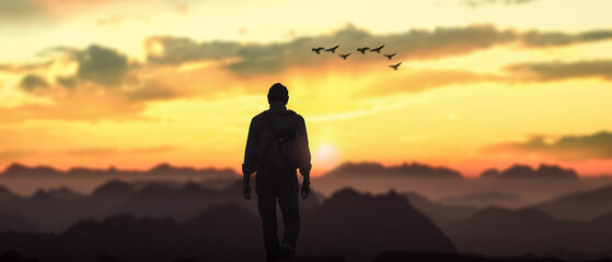 Silhouette of a man against the sunset landscape.