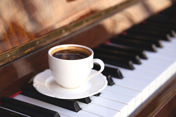 White cup of black coffee on retro piano keys © svitlini
