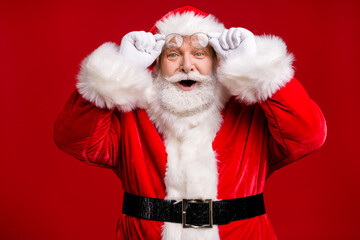 Photo of retire old man grey beard take off hold specs smile excited smile can't believe christmas miracle wear santa costume belt gloves coat spectacles headwear isolated red color background