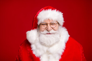 Photo of pensioner old man grey beard wait listen children sitting knee make wish smiling prepare show giftbox wear santa costume coat spectacles headwear isolated red color background