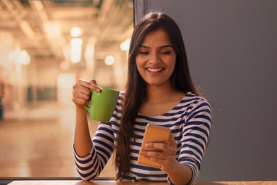 Woman looking at her phone with a coffee mug in her hand	