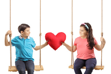 Children on a swing holding a red heart and looking at each other