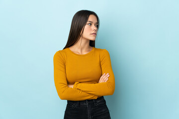 Teenager girl isolated on blue background keeping the arms crossed
