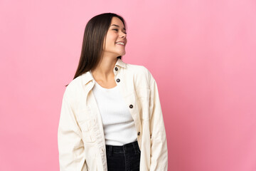 Fototapeta premium Teenager girl isolated on pink background looking to the side and smiling