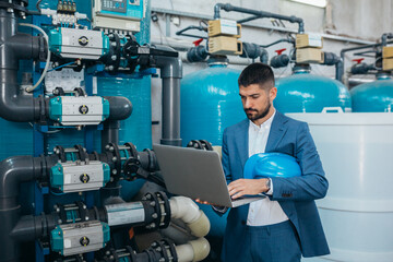 business man using laptop computer in front of chemical treatment equipment