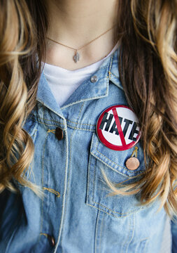 Female wearing a jean jacket and an anti-hate button