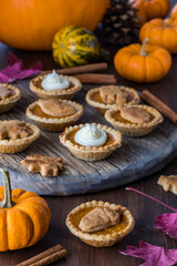 Decorated pumpkin pie tarts surrounded by fall decorations.