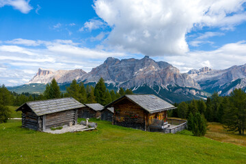 Hiking in the Dolomites - beautiful mountain panorama Piz de Medesc (Medesspitze) and Cima Cunturines (Cunturines-Spitze) in the background and traditional huts in the foreground, South Tyrol Italy