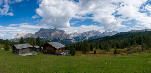 Fototapeta na wymiar Hiking in the Dolomites - beautiful mountain panorama in the background and traditional huts in the foreground, South Tirol Italy