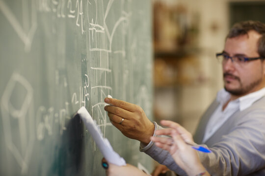 Professor in front of blackboard giving a lesson to the students