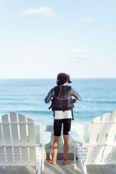 Child in sailing gear looks out at the ocean conditions