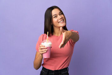 Teenager girl holding a strawberry milkshake shaking hands for closing a good deal
