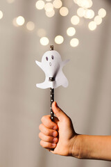 A drinking straw with a Halloween decor in the hands of a child. Paper Ghost with your own hands.