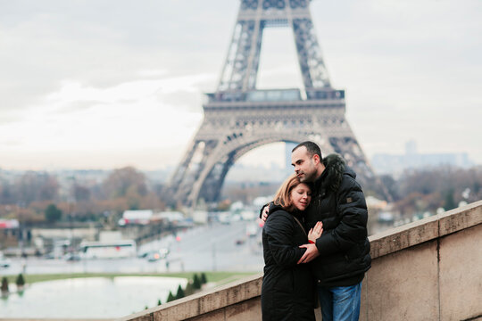 Happy couple kissing and hugging in front of the Eiffel Tower in Paris
