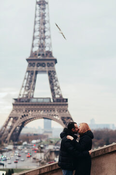 Happy couple kissing and hugging in front of the Eiffel Tower in Paris