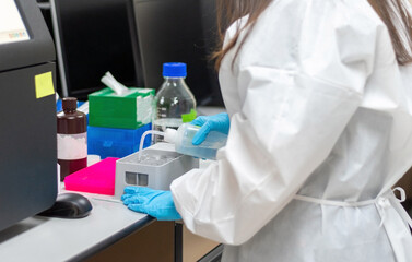 Med lab technologist using DNA sequencing equipment in science room. Chemist or scientist wearing blue medical glove working in hospital or university research laboratory.