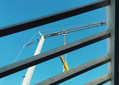 Crane at work seen through unfinished roof's beams