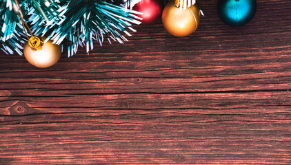 Beautiful Christmas card with a green Christmas tree and frosted balls on a brown wooden background. Christmas tree with small colorful balloons.