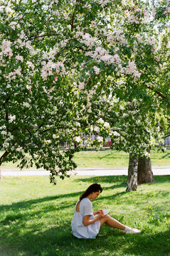 Woman sitting under apple tree in blossom