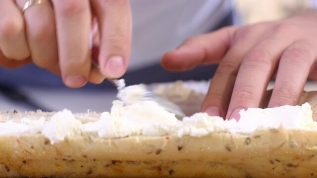 Cooking delicious sandwich of baguette vegetables ham and cheese in kitchen home. male chef spreads cream cheese on crunchy bun prepare sandwich. Morning Breakfast and lunch. Fast street food