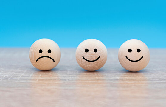 Three wooden faces, happy and sad faces, concept picture about mood of people 
