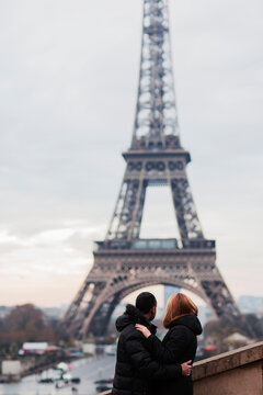 Happy couple kissing and hugging in front of the Eiffel Tower in Paris
