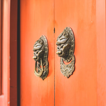 Close-up of ancient gold handle, knocker on red door in Chinese architecture