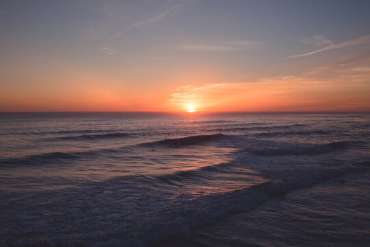 Wide view of the sunset and surfers in the ocean