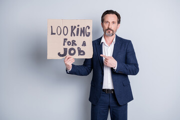Photo of dismissed mature guy business protest financial crisis company crash lost job direct finger hold carton placard labor market entrepreneurs strike wear suit isolated grey background