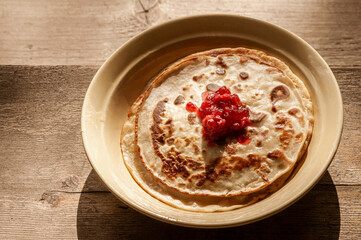 plate with Russian pancakes and cranberry jam