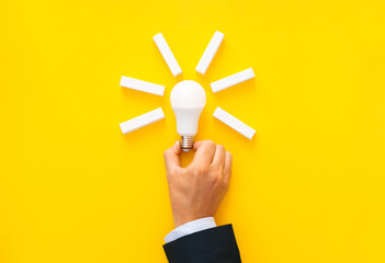 Businessman holding light bulb with wooden blocks with copy space. Business start-up goals to...