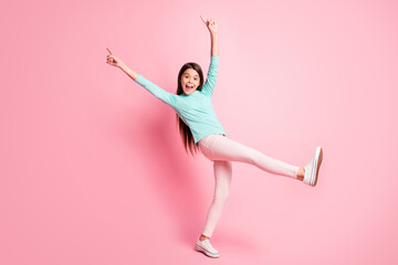 Full body size photo of cute pretty little hispanic lady long hairstyle dance raise hands up direct fingers wear turquoise sweatshirt pants white sneakers isolated pink color background