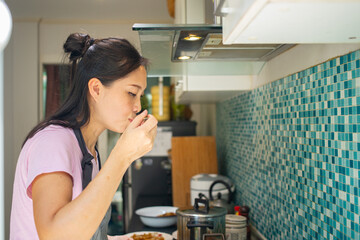 Asian woman using spoon for  tasting soup