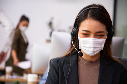 Asian Call Center With Mask  For Hygiene In Their Office.