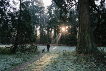 Female walking her dog on a misty and frosty morning at sunrise.